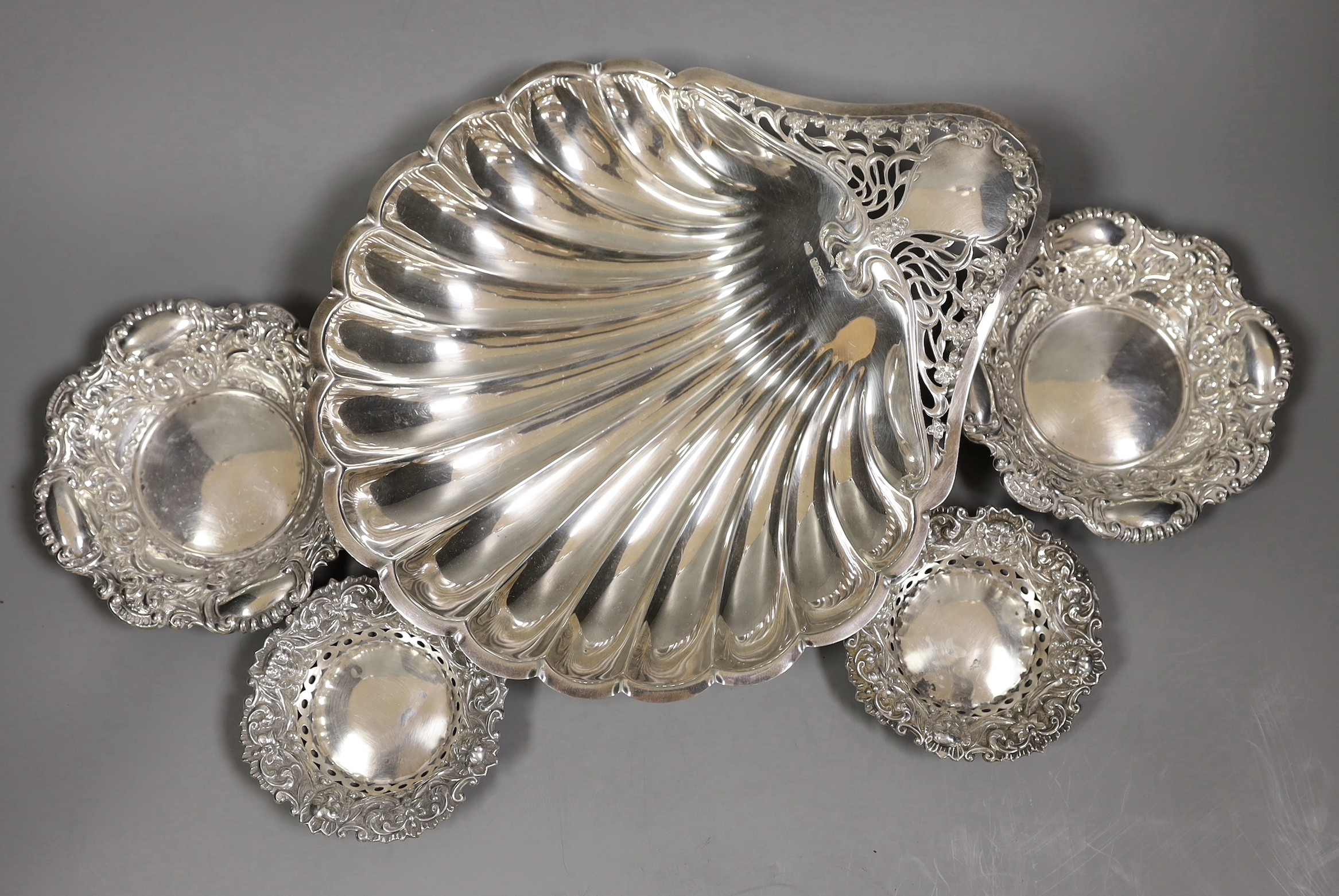 An Edwardian Art Nouveau silver shell dish, with pierced handle, on ball feet, Atkin Brothers, Sheffield, 1905, 28.3cm, together with two small pairs of repousse silver bonbon dishes, 16oz.